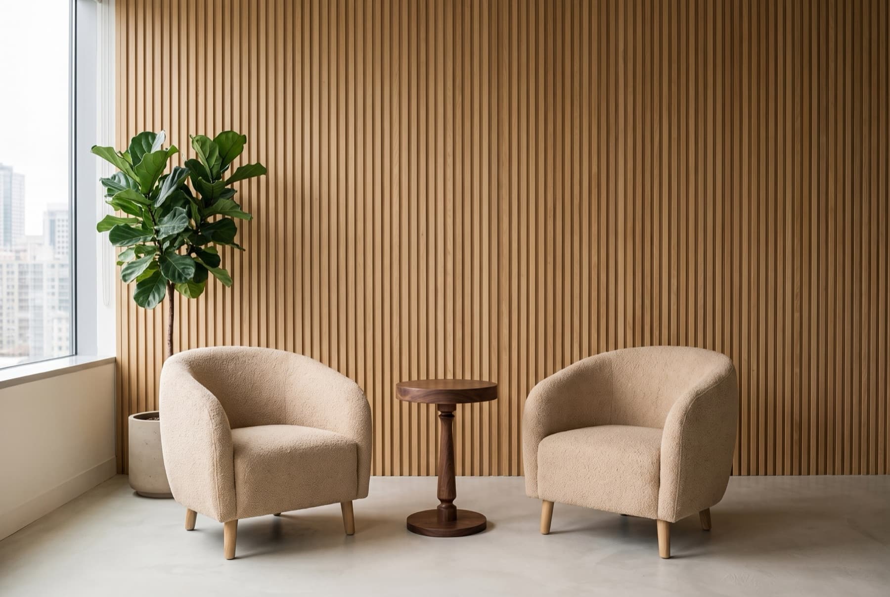Workplace lounge with a fluted timber wall, two bouclé tub armchairs and a walnut pedestal side table