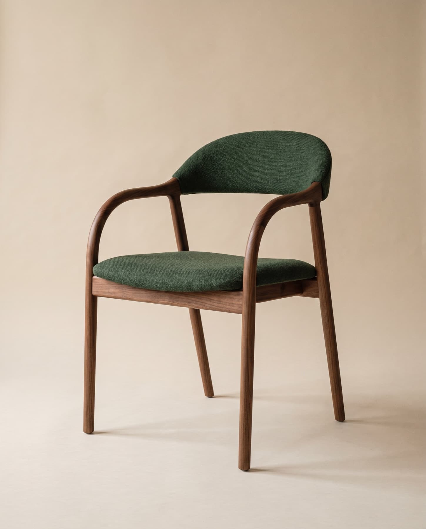 Vale dining armchair in walnut whose arms sweep into the back, upholstered in forest wool