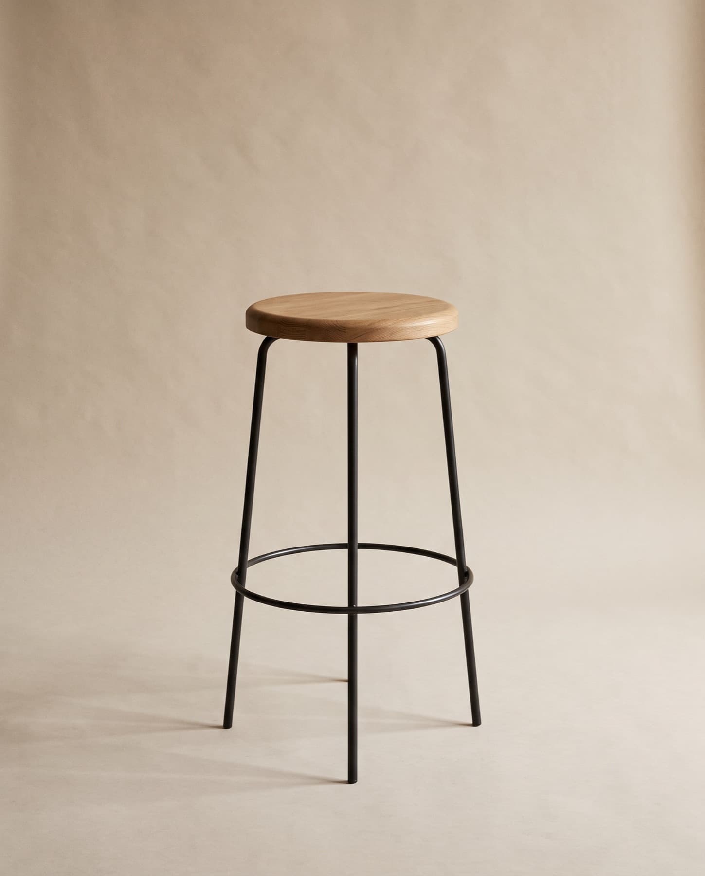 Mira counter stool: a blackened steel frame and footring with a round oak seat
