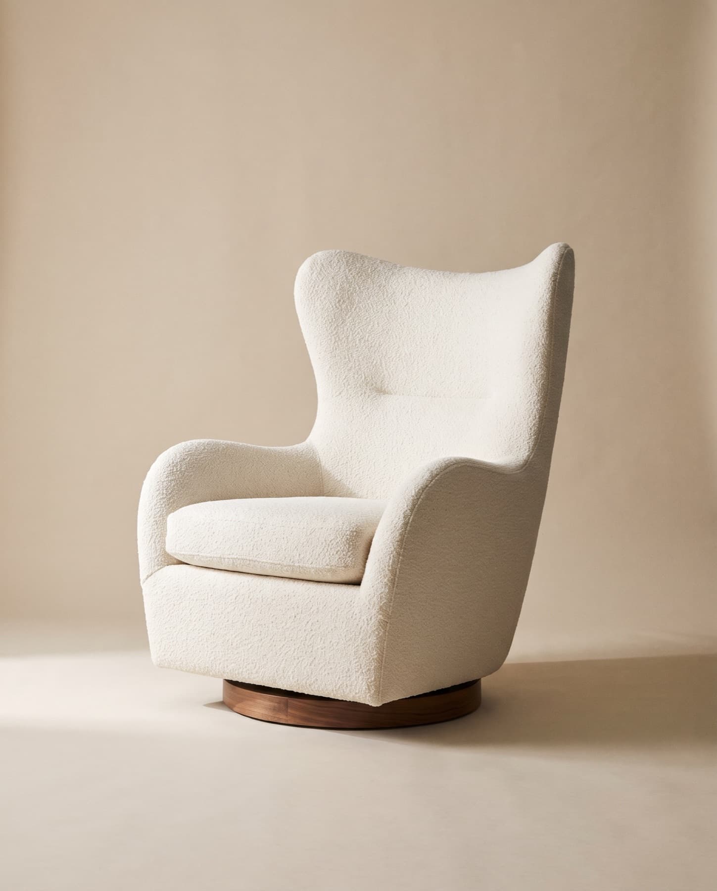 Aurel high-backed swivel lounge chair in ivory bouclé on a low walnut base