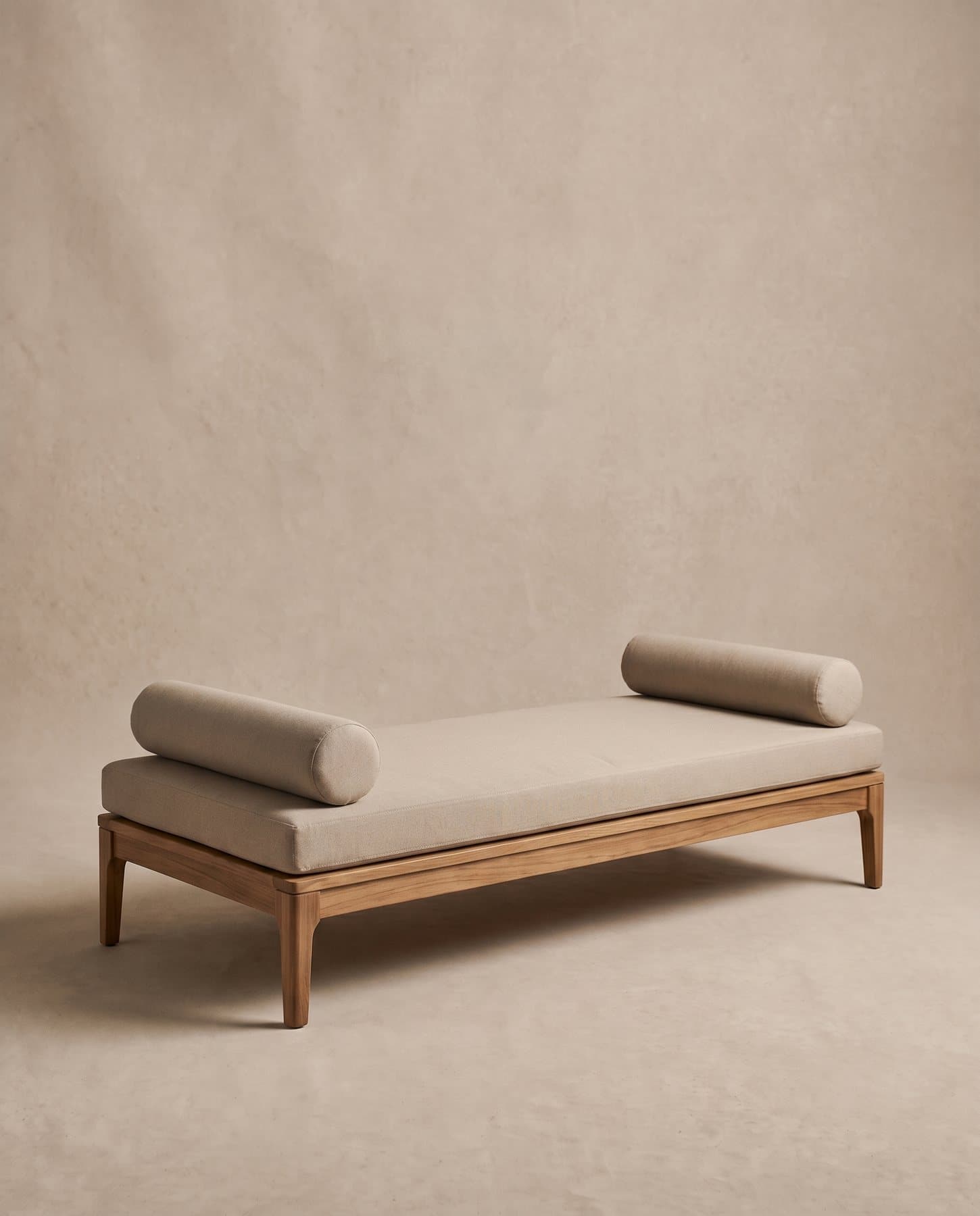 Dune outdoor daybed: a low teak frame with a sand canvas mattress and two round bolsters