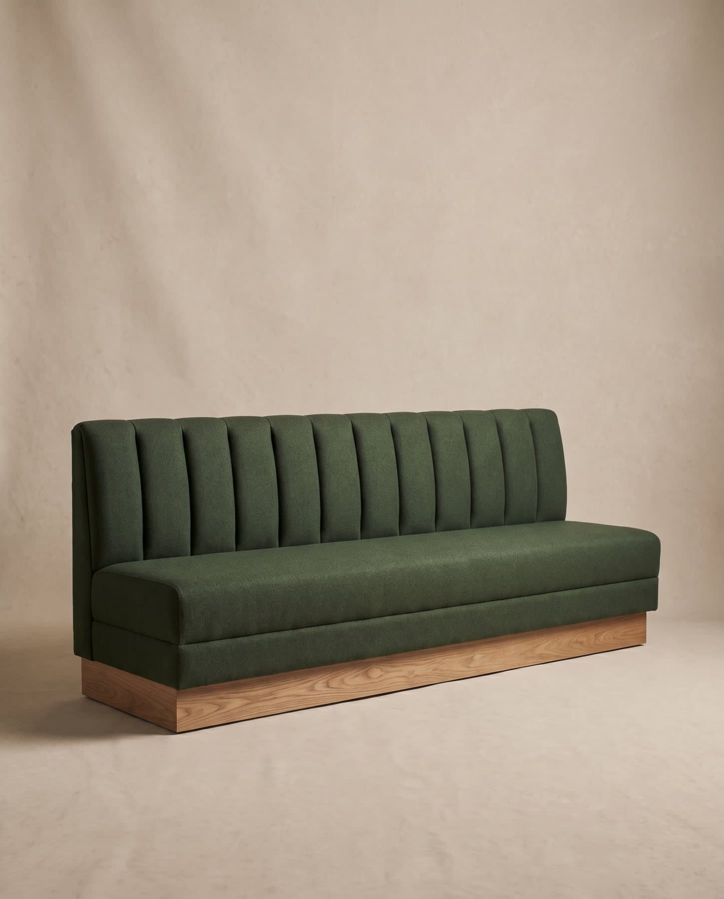 Alcove banquette in forest-green wool with a channel-tufted back on an oak plinth