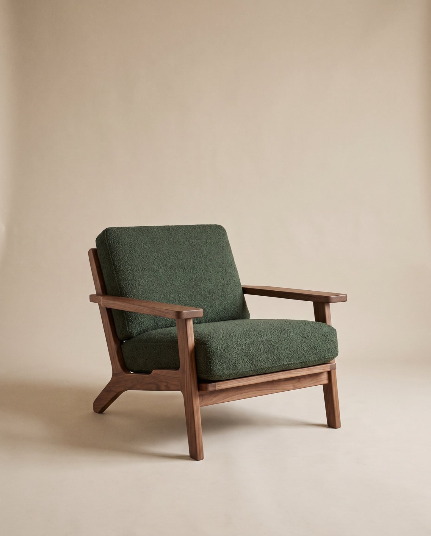 Sella lounge chair: open walnut frame with flat arms and loose forest-green wool cushions
