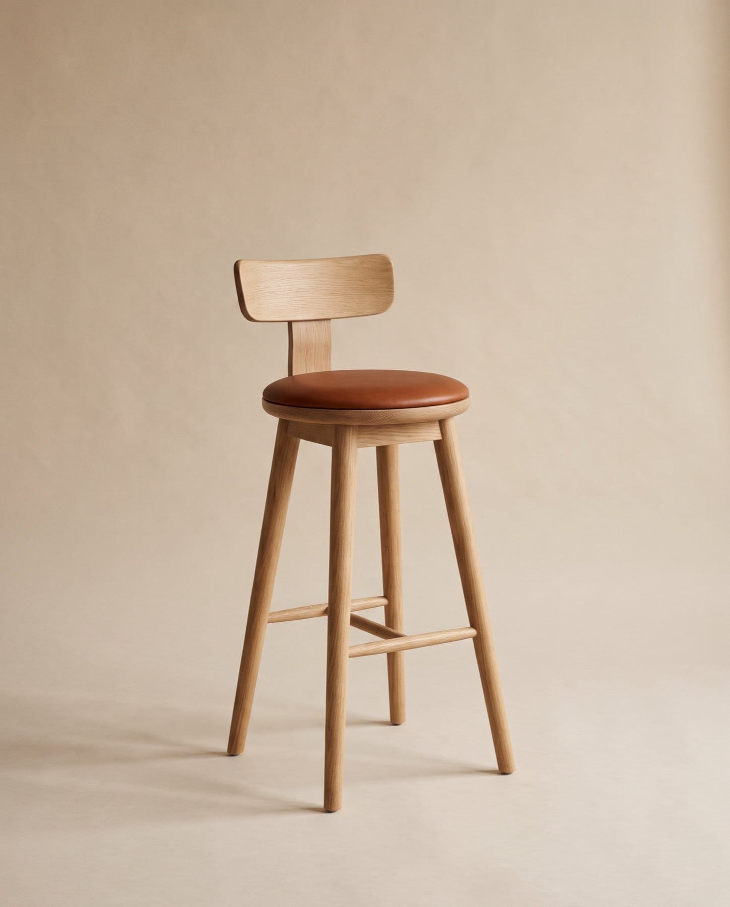Lune bar stool in oak with a round cognac leather seat, a shaped back rest and a footrest