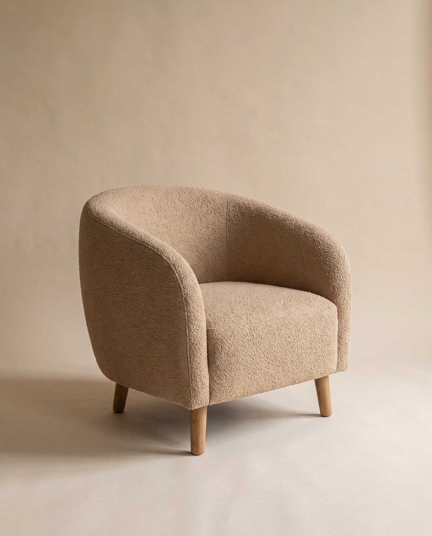 Oris tub armchair upholstered in sand bouclé on four tapered oak legs