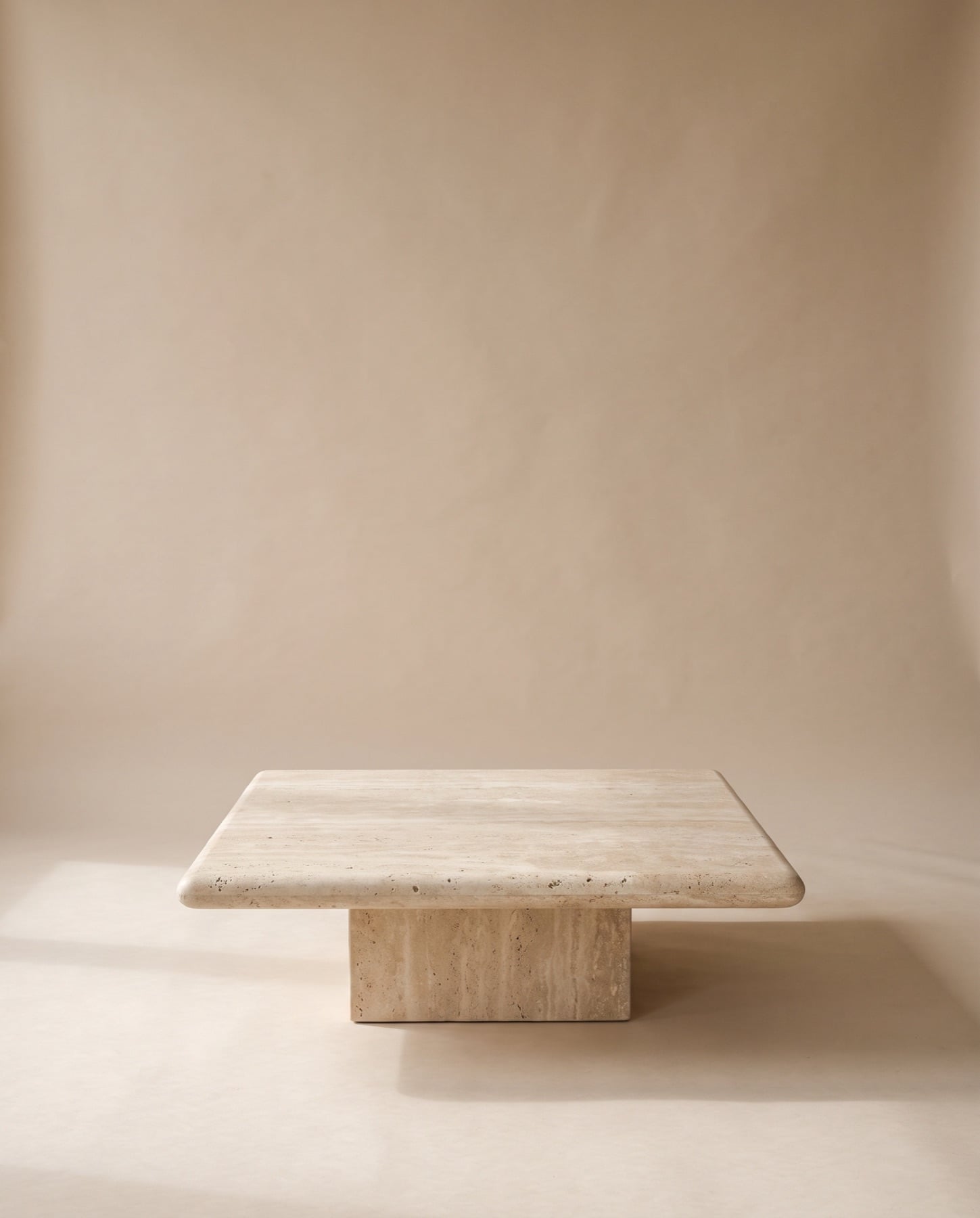 Plinth coffee table: a thick honed travertine top on a recessed travertine block