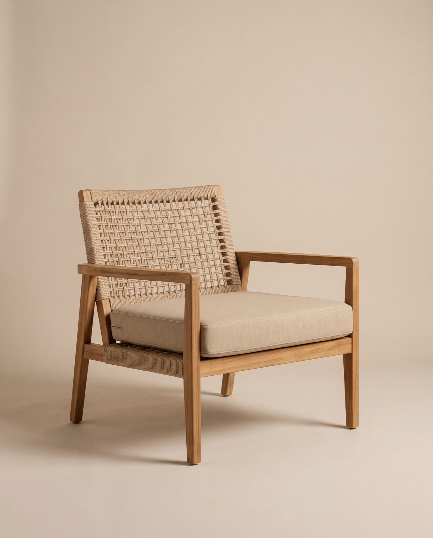 Riva outdoor lounge chair in teak with a woven natural rope back and a sand seat cushion