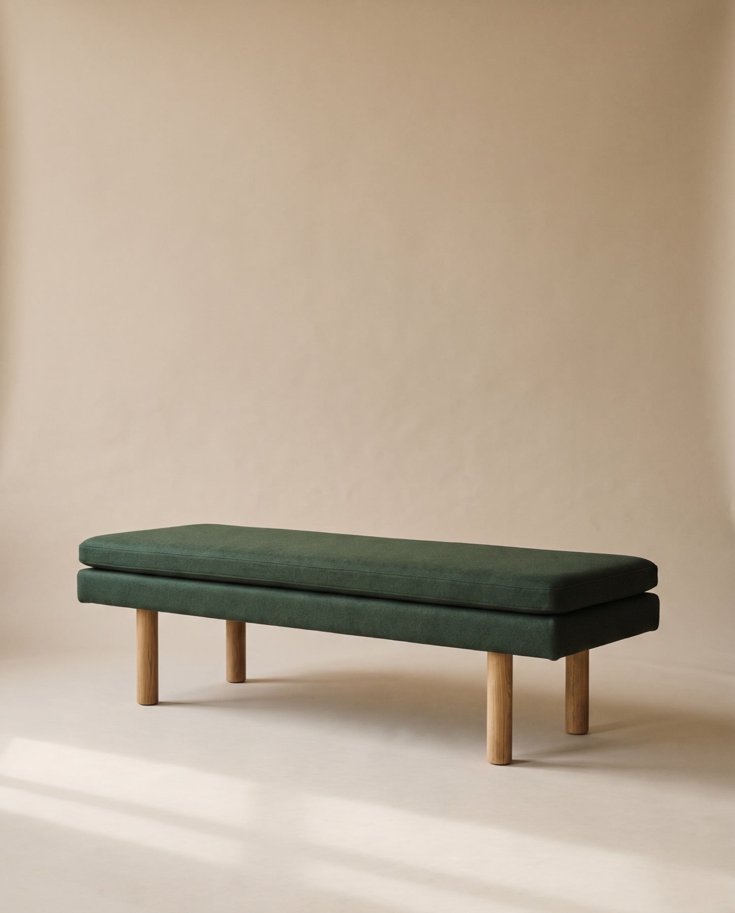 Tessa bench upholstered in forest-green wool on four round oak legs