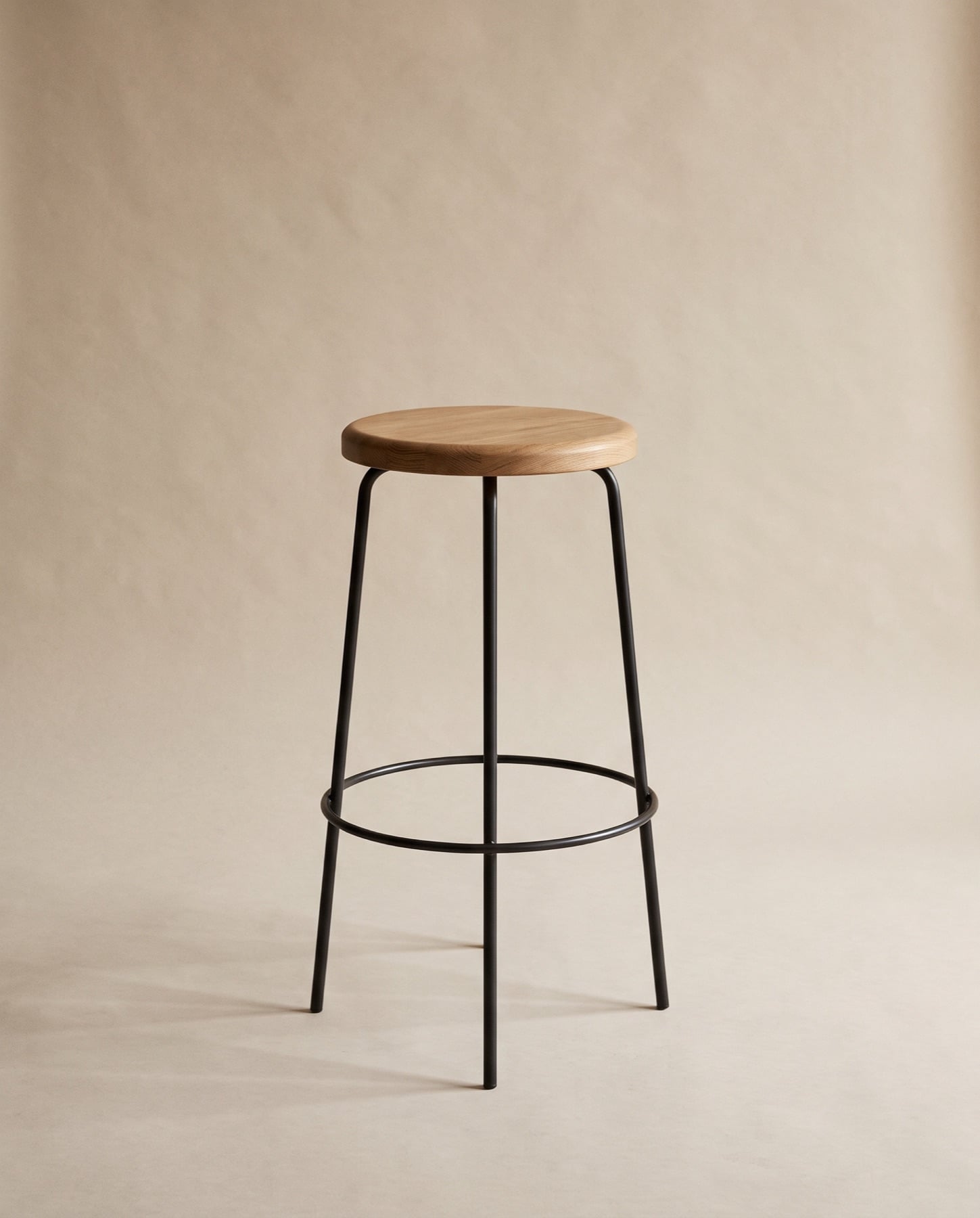 Mira counter stool: a blackened steel frame and footring with a round oak seat