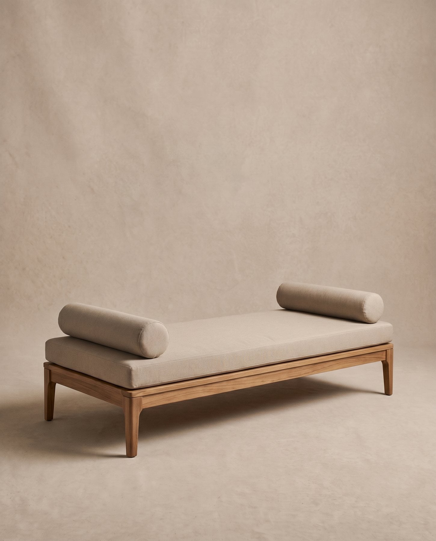 Dune outdoor daybed: a low teak frame with a sand canvas mattress and two round bolsters