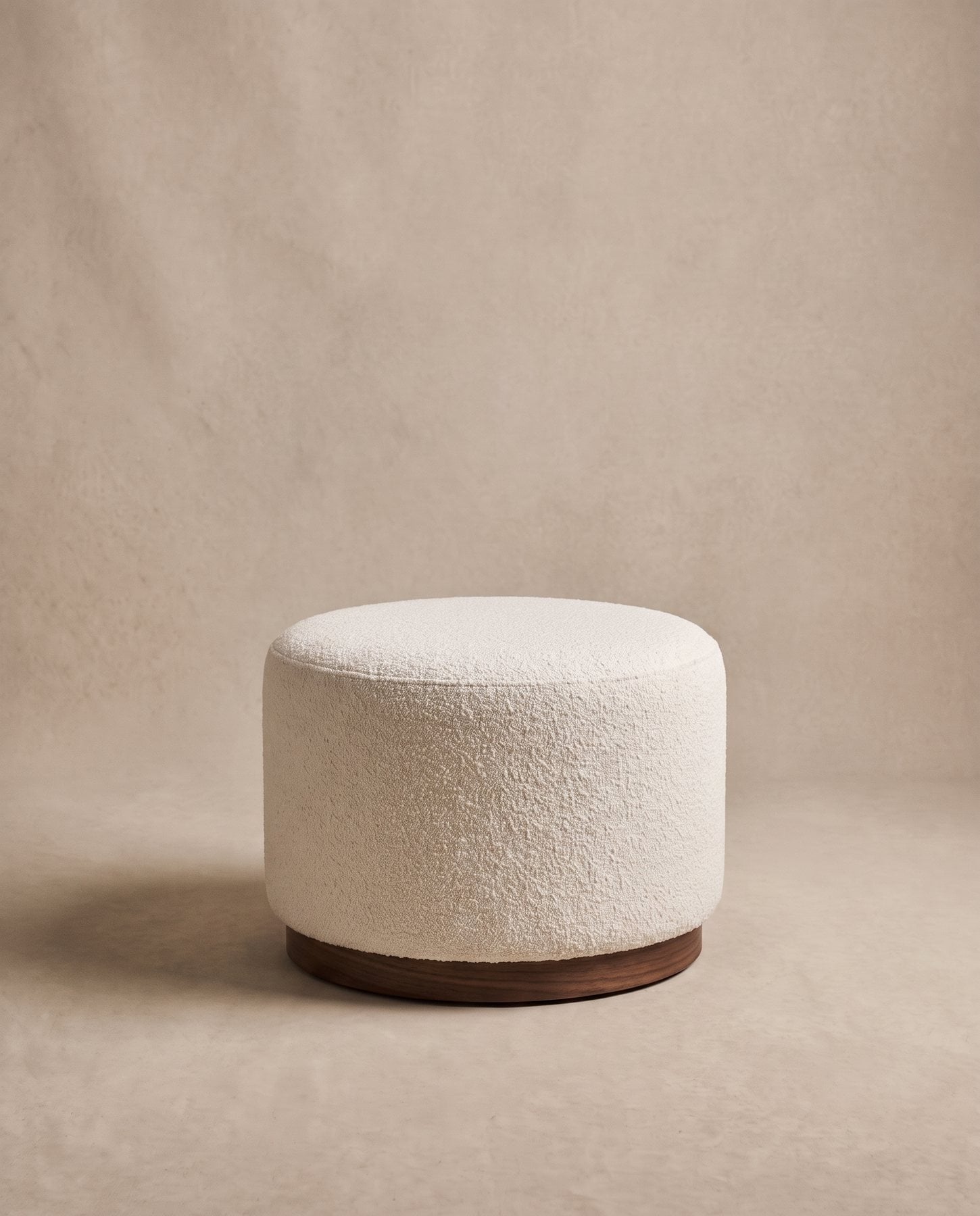 Tuft round ottoman in ivory bouclé on a recessed dark walnut base